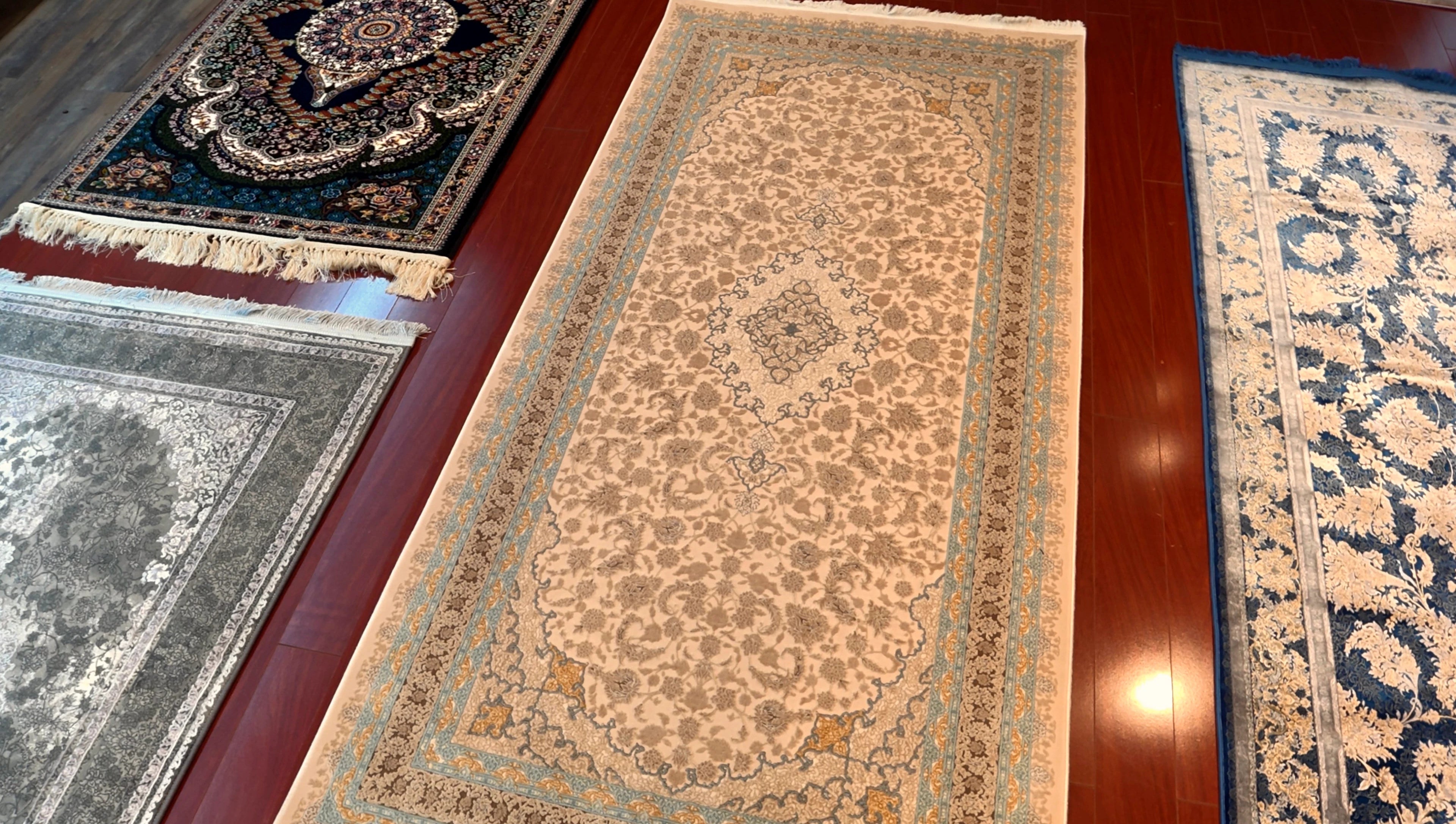 Four patterned rugs displayed on a wooden floor.