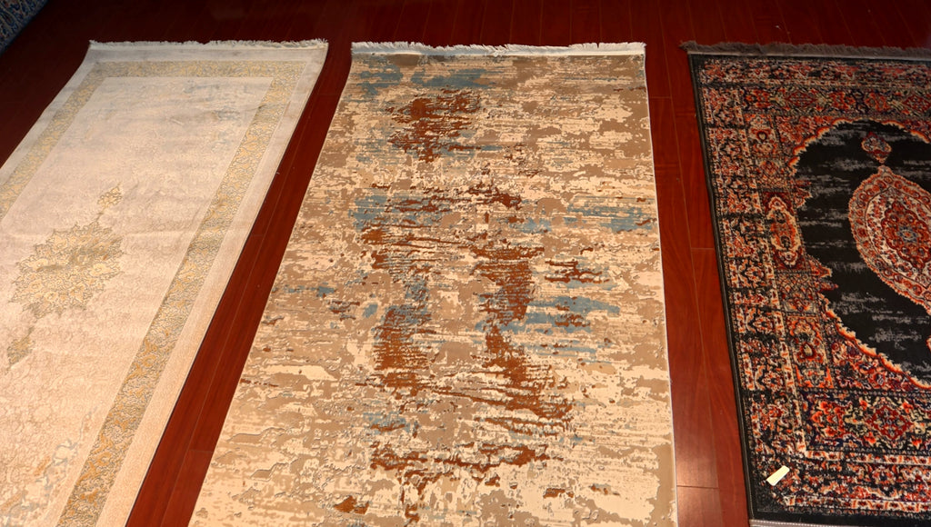 Three rugs of different designs and colors on a wooden floor.